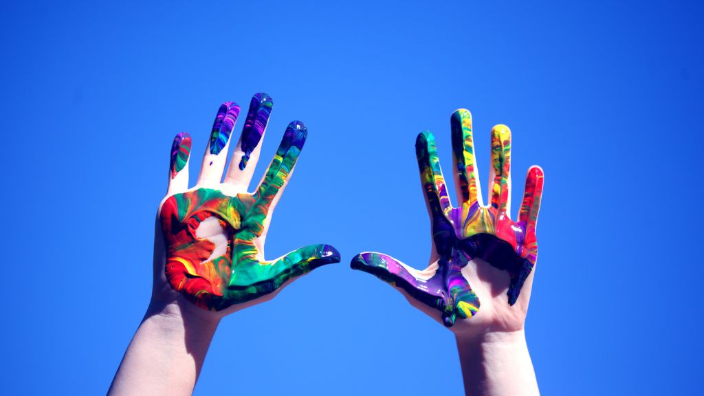 paint-smeared hands in almost every colour in front of the sky