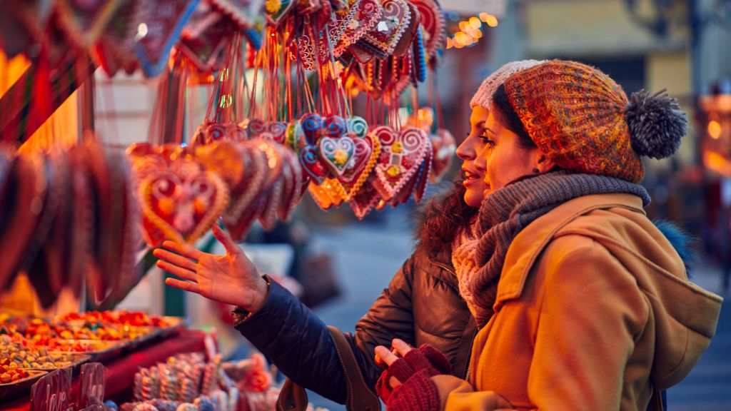 two women look at handcrafted hearts on a market stall, they are delighted